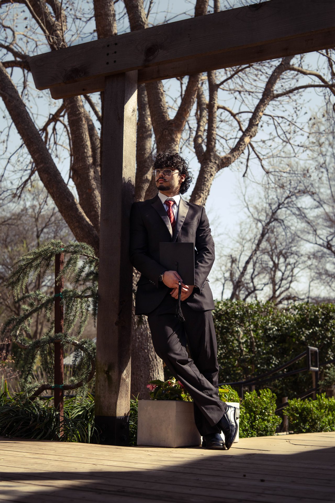 Graduate posing on stone steps in cap and gown, DFW graduation photographer